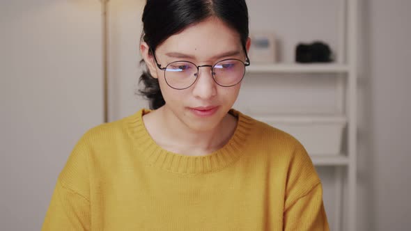 Asian woman wearing glasses using a laptop.