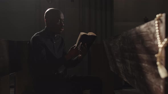 Rosary Beads and African-American Clergyman Reading Bible on Background