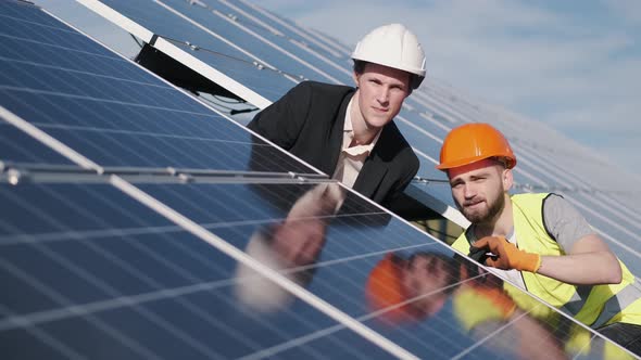 Businessman and Worker Are Checking Solar Batteries Together Outside