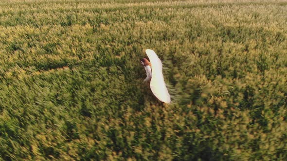 Lady Silhouette Walks Along Field Holding Glider Wings