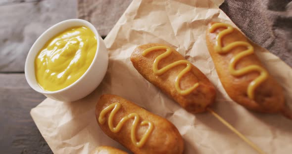 Video of corn dogs with dip on a wooden surface