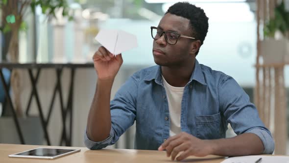 Young African Man Flying Paper Plane While Working in Modern Office