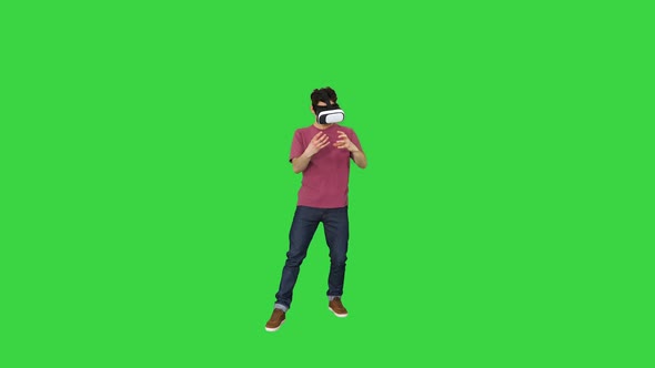 Amazed Man Using VR Headset Glasses Touching and Interacting with Virtual Reality World on a Green