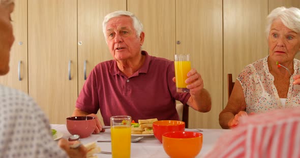 Senior man toasting his glass while having meal with friends