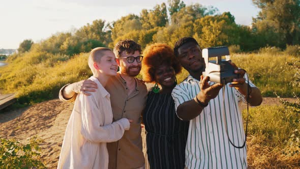 Diverse Group of College Friends Taking Funny Selfies with a Vintage Instant Camera Chilling Near