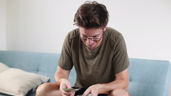 Men's Hands Count Cash Dollars and Other Currencies at Home in a Bright Room