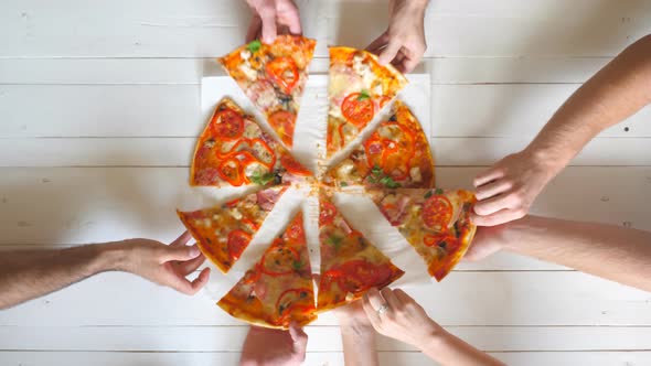 Top View Male and Female Hands Taking Slices of Pizza with Cheese, Tomatoes and Ham From Food