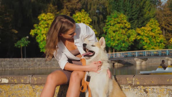 Young woman walking her cute Akita Inu dog in park on sunny day. Lovely pet