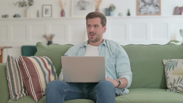 Young Man with Laptop Coughing on Sofa