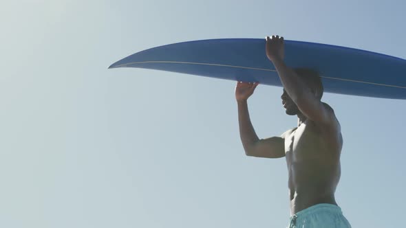African American man holding a surfboard on his head