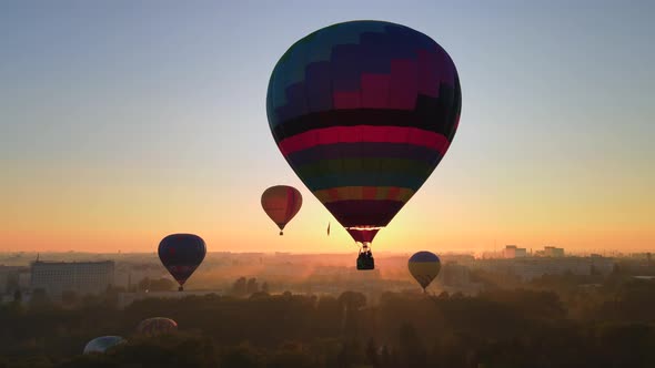 Aerial Drone View Silhouette of Colorful Hot Air Balloon Flying Over Green Park in Small European