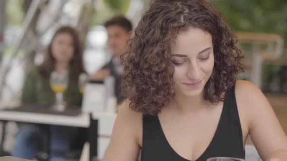 Pretty Young Curly Woman Eating Tasty Meat Dish with Potato at Street Cafe