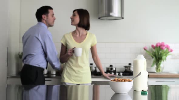 Couple in kitchen, man kissing wife and leaving