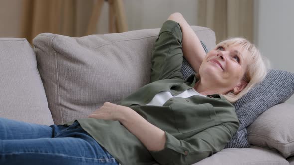 Happy Relaxed Middleaged Pensive Dreaming Woman Rest on Couch at Home Enjoy Peaceful Mood Sleepy