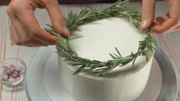 Chief Decorates Christmas White Cream Cake with Rosemary Wreath and Cranberries