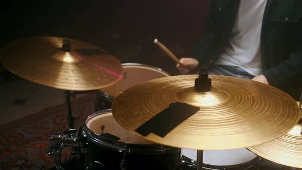 Drummer Playing the Drum Set in a Dark Room on a Black Background