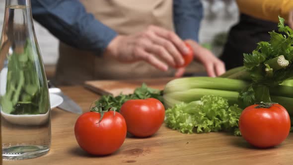 Cooking Salad at Home Man Hand Takes a Red Tomato for Slicing