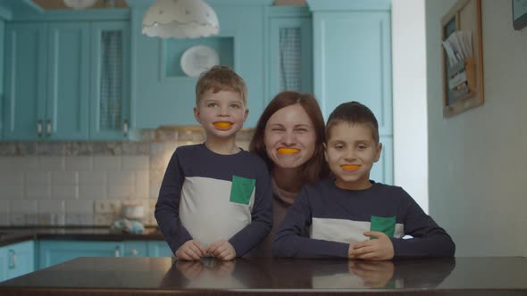 Funny family playing with orange peels in their mouth