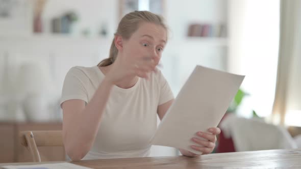 Beautiful Young Woman Reacting to Loss on Documents in Office