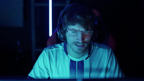 Portrait of a Man Gamer in Headphones Plays a Video Game Cyber Sportsman at the International