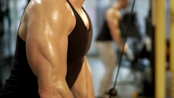 Sweaty sportsman working out in gym by doing pull-downs, upper body close-up