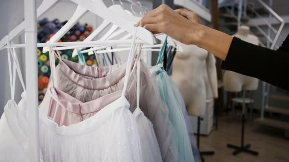 Hands of Unknown Woman Who Choosing Colorful Tulle Skirts Hanging on Hangers at Sewing Workshop