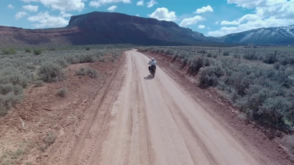 Aerial drone view of a motocross motorcycle driving off-road on a dirt road in Moab, Utah.