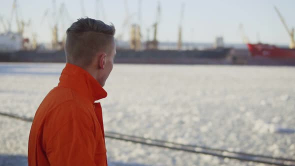 Harbor Worker in Orange Uniform is Walking By the Sea