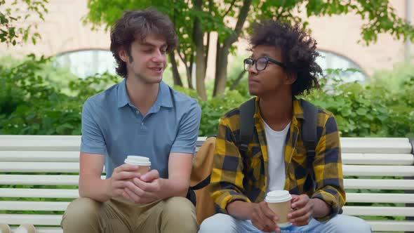 Multiethnic College Students Sitting on Bench Relaxing After Classes Drinking Coffee