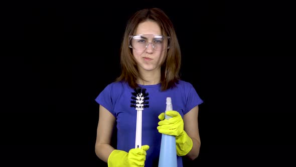 A Young Woman Scratches Her Head with a Toilet Brush. Woman in Safety Glasses and Gloves with Tools