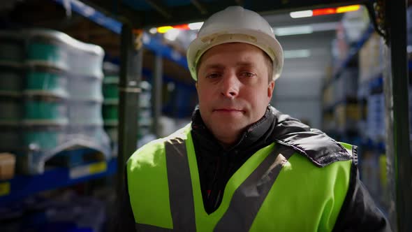 Closeup Portrait of Experienced Caucasian Male Forklift Driver in Hard Hat Sitting in Vehicle