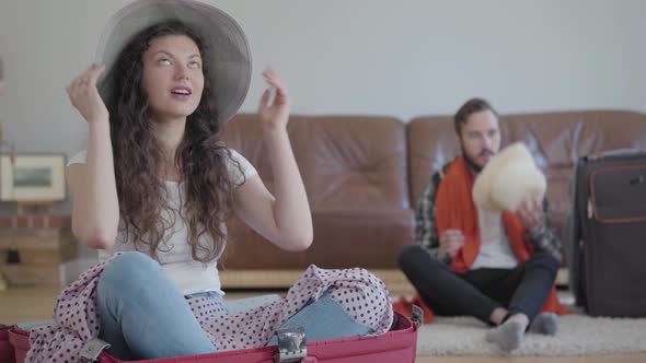 Portrait Happy Man and Woman Sitting on the Floor Packing a Suitcase Before Travel at Home