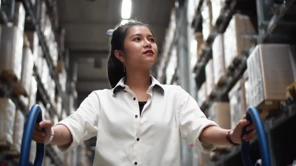 Young woman walks with shopping cart walking for choosing new furniture in big store warehouse	