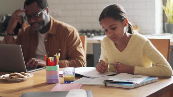 Positive man working on laptop while his daughter doing homework