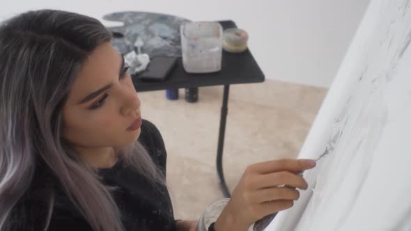 Latina Woman Concentrate On Applying Paint On White Canvas. - close up