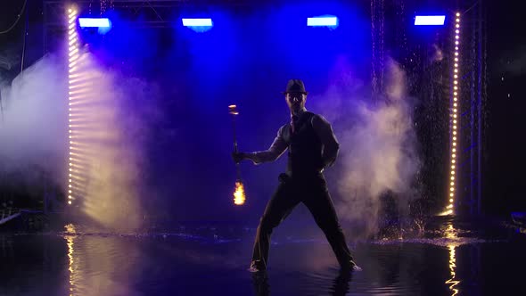 Fireshow Performance with Burning Torch Performed By a Man in a Suit and Hat. Fire Show in the Rain