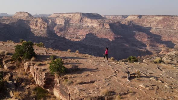 Aerial woman hiking on the edge of the San Rafael River Canyon in Utah