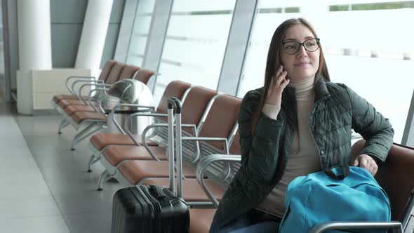 Happy Woman Is Talking on Mobile Phone Waiting Her Flight in Airport.