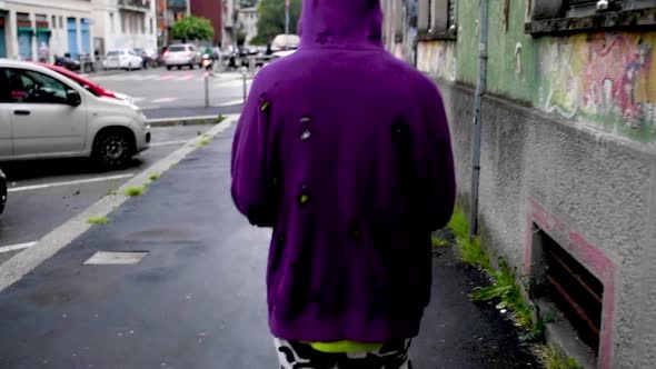 Rear view of young man wearing purple hoodie and walking in city