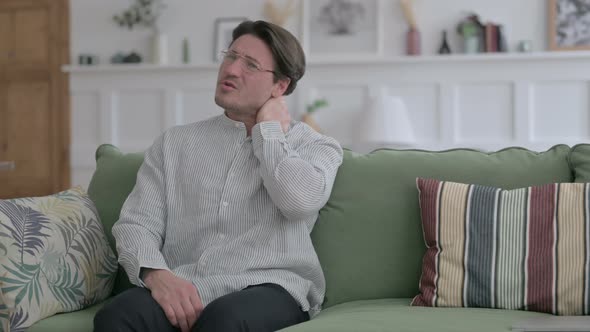 Man having Neck Pain while Sitting on Sofa