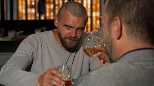 Handsome Man Clinking Whiskey Glasses with His Friend at the Bar