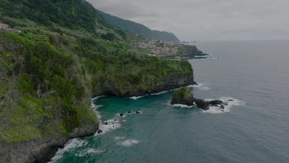 Dramatic volcanic Madeira coastline covered with greenery; cinematic aerial