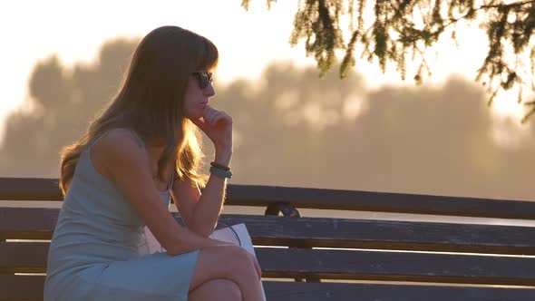 Lonely Woman Sitting on Lake Side Bench Enjoying Warm Summer Evening