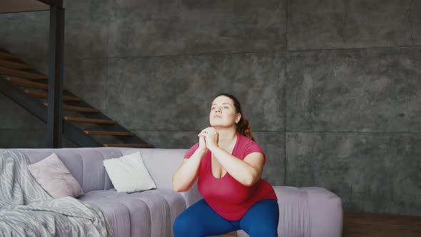 Overweight Young Woman Exercising to Lose Weight Practicing Squats at Home
