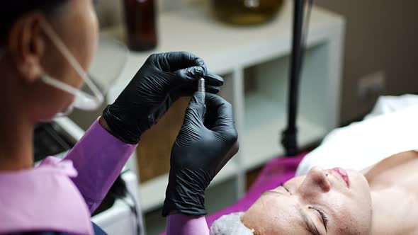 Permanent Makeup Cosmetologist Master Preparing a Needle for the New Shape of the Eyebrows of Model