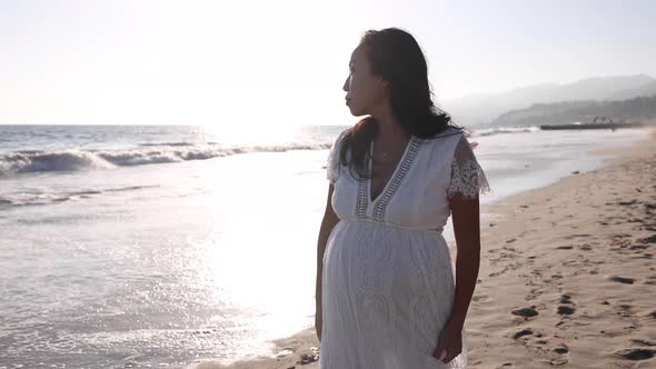 Pregnant Asian woman enjoying walk on the beach