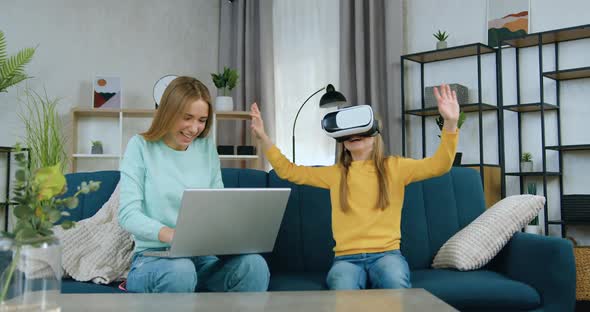 Girl Choosing Virtual Entertaintment for Her Younger Sister which Sitting Near Her on soft couch