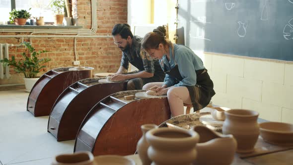 Slow Motion of Male and Female Ceramists Working with Pottery Wheels in Studio