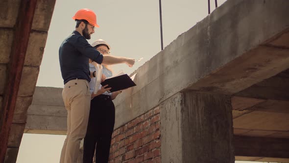 Two Architects Working On Building Model Blueprints. Engineers In Safety Helmet Construction House.