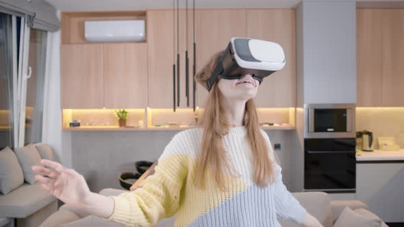 Young girl at home in reality glasses plays, communicates, uses at home in a VR helmet